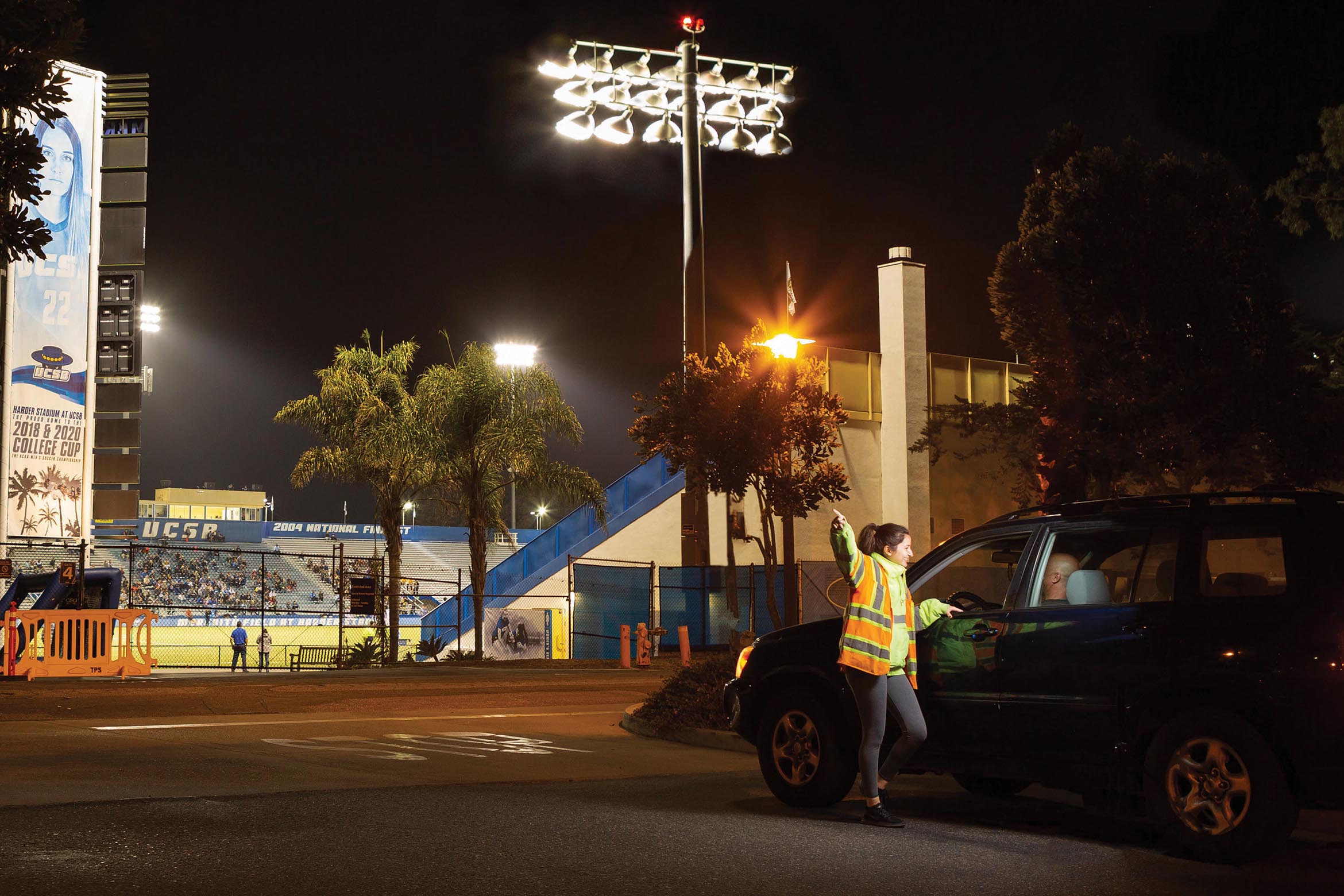 TPS student worker directing traffic at an evening event at Harder Stadium