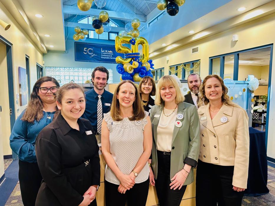 "a celebratory photo of conference service staff in their office with balloons"