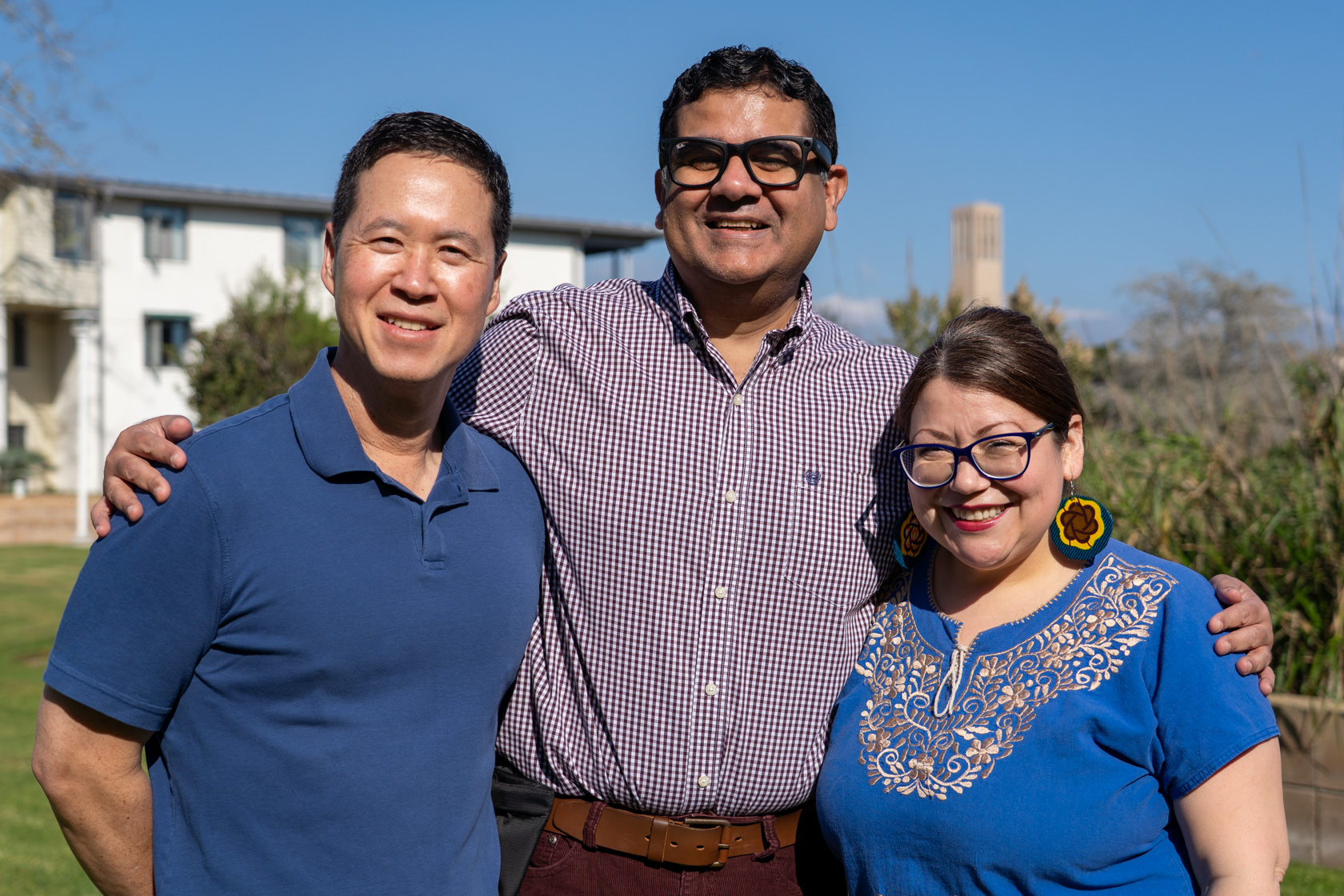 Three faculty members standing in front of a building.