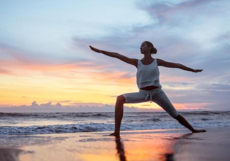 woman practicing yoga on the beach