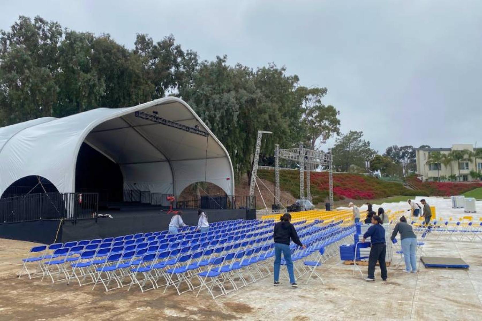 commencement stage on the left and student workers setting chairs up on the right