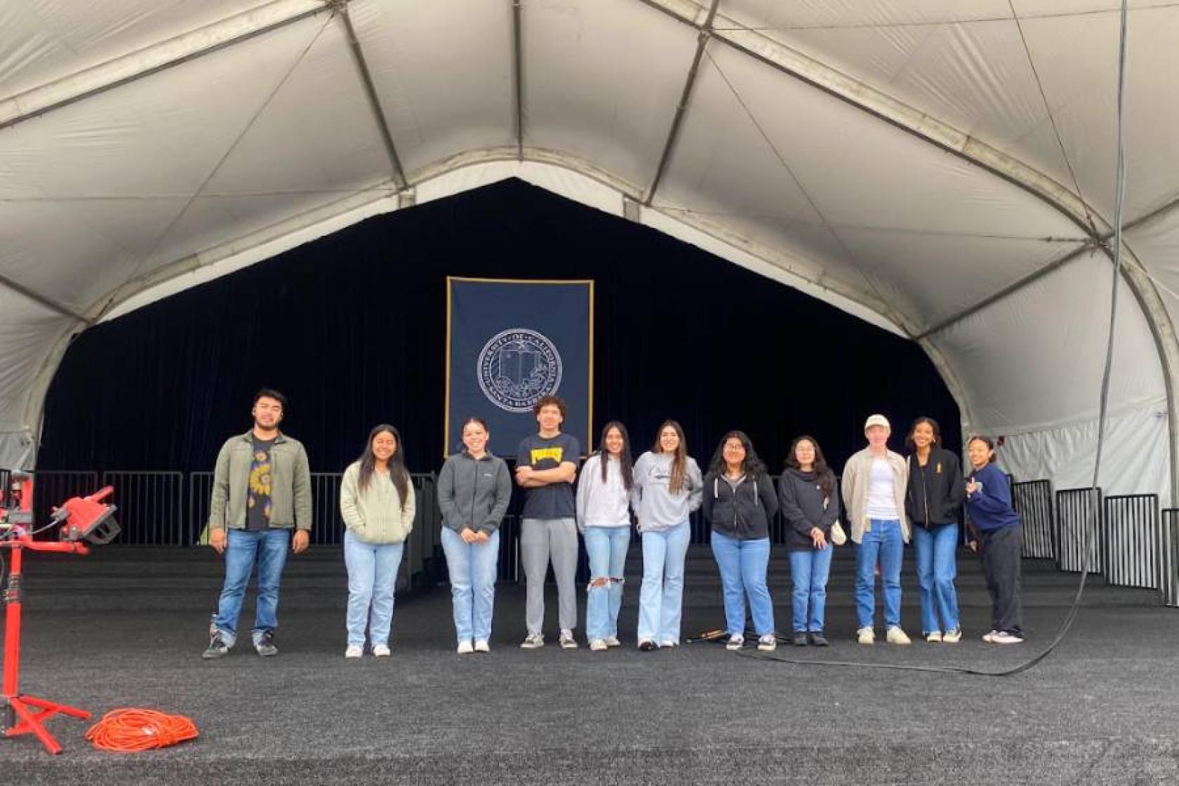 student workers standing in a row on the commencement stage 